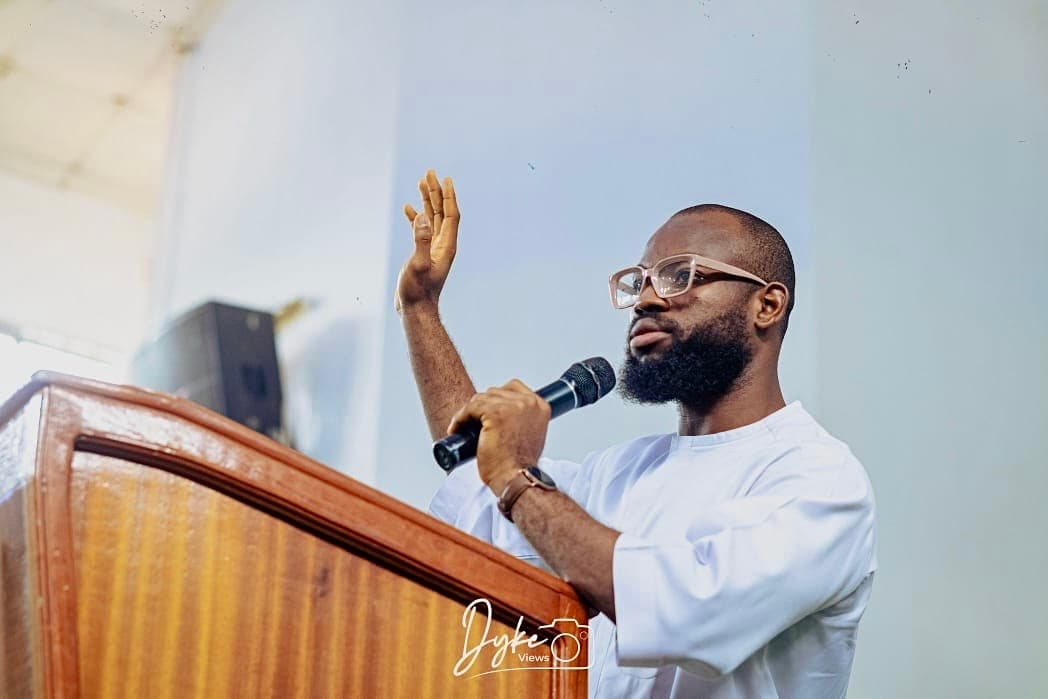 David Ejere speaking at the podium, hand raised